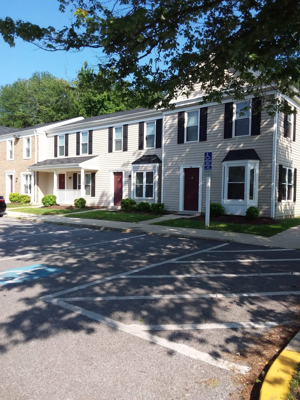 A row of two-story townhouses at Indian Head Village seen from the parking lot, with dark red doors, bay windows, and a covered porch